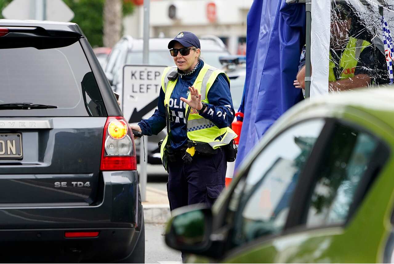 A Queensland police officer stops a motorist at a checkpoint at Coolangatta on the Queensland-New South Wales border, Friday, May 22, 2020.