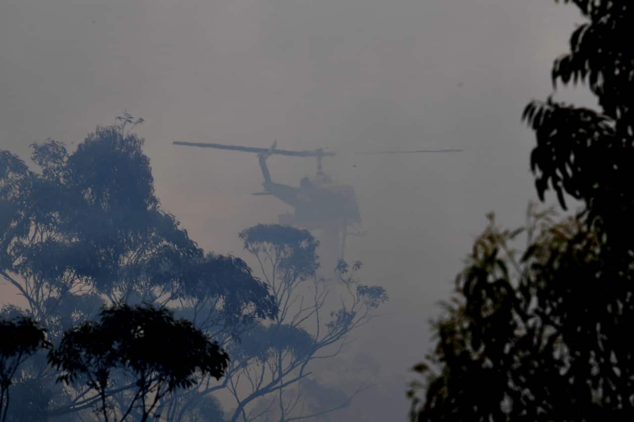 A water bombing helicopter helps to contain the Gospers Mountain Fire