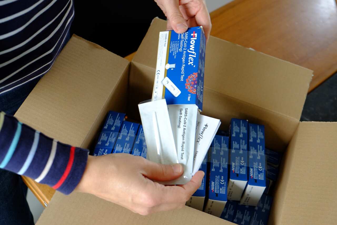 Illustration picture shows  a woman receiving and unboxing a postal package with FlowFlex SARS-CoV-2 Antigen Rapid Tests for self-testing. 