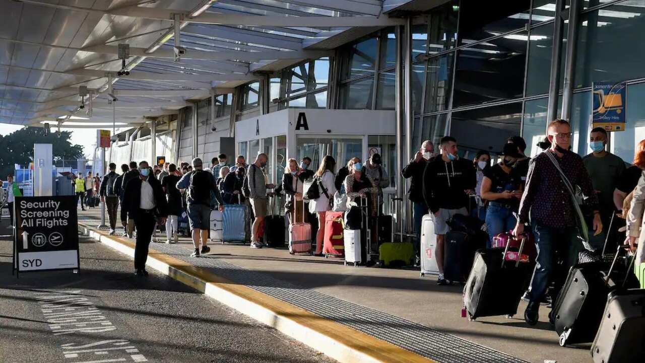 Queues of people are stretched outside the Virgin and Jetstar departure terminal at Sydney Domestic Airport.