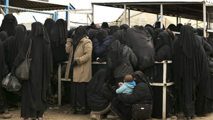  a woman waits with her baby for aid supplies at Al-Hol camp, in Hassakeh province, 