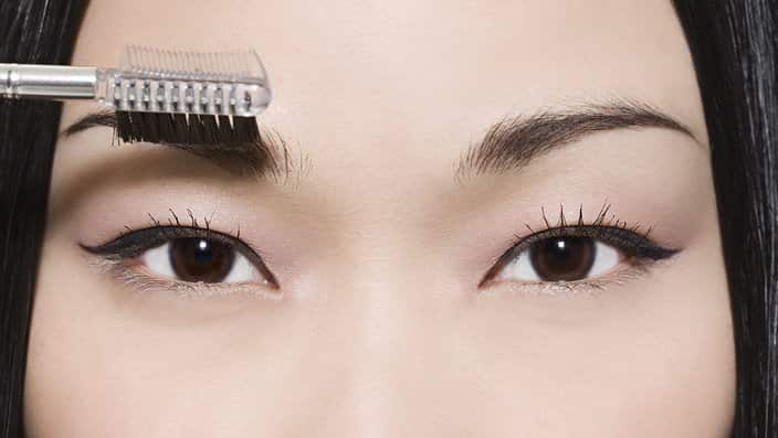 Woman combing her eyebrow