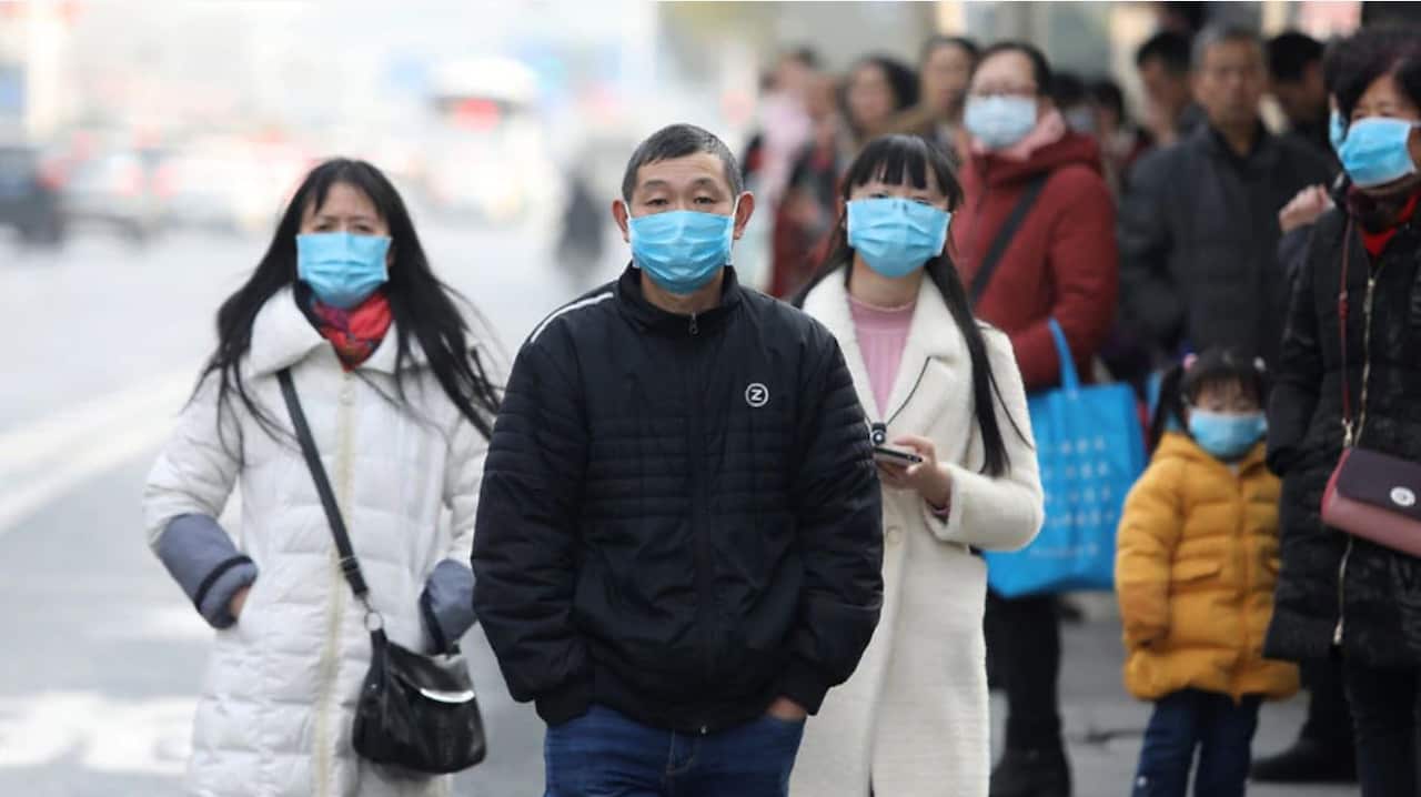 Chinese residents wear masks while waiting at a bus station near the closed Huanan Seafood Market, which has been linked to cases of a new strain of Coronavirus.