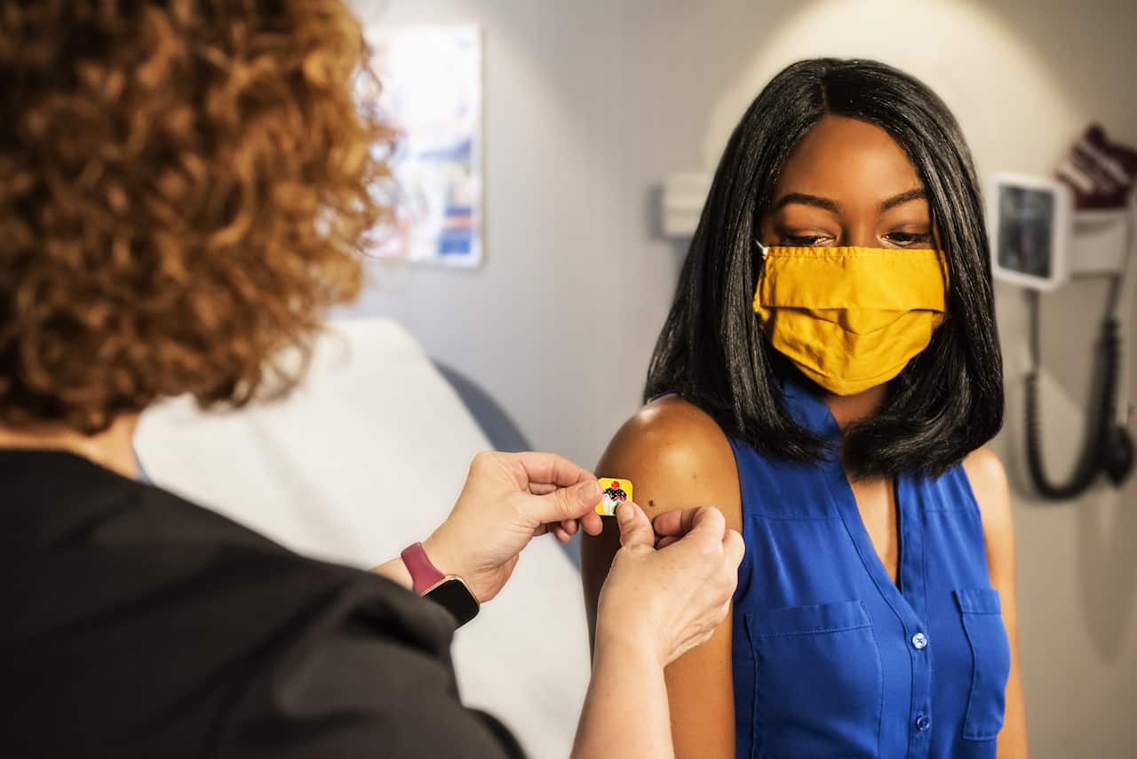 In this 2020 photograph, captured inside a clinical setting, a health care provider and patient, consult on influenza vaccine options.