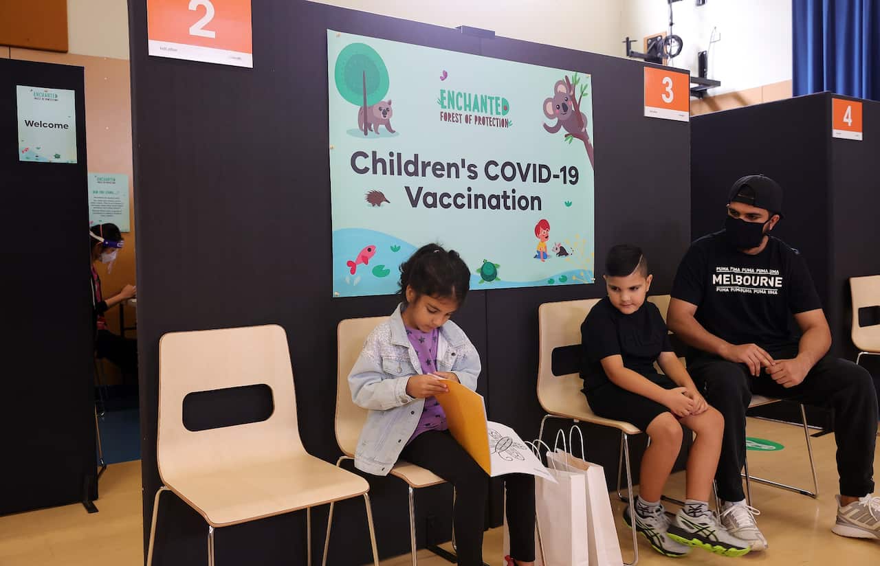 Twins Attiqunissa (left) and Imran (right) with their father Idris Khalid (far right) at a pop-up vaccination clinic at Movelle Primary School in Kings Park, Melbourne, Saturday, January 29, 2022. (AAP Image/Con Chronis) NO ARCHIVING