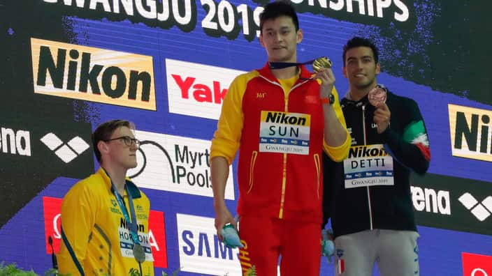 China's Sun Yang, holds up his gold medal as silver medalist Australia's Mack Horton, stands away from the podium 