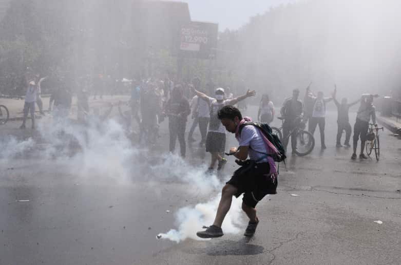 A protester kicks a tear gas canister during clashes with police in Santiago, Chile.