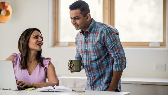 Husband and wife using laptop in kitchen