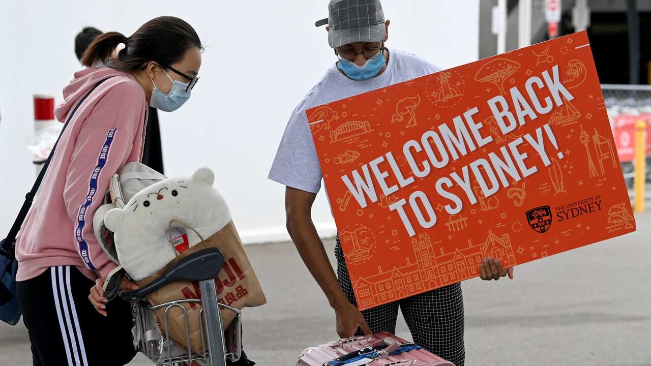 University representatives hold signs as international students arrive at Sydney Airport in Sydney, Monday, December 6, 2021. 