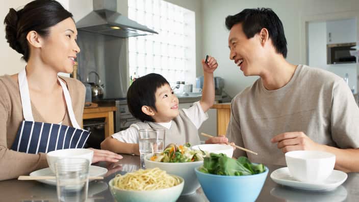 Young Family sitting at kitchen table interacting before meal