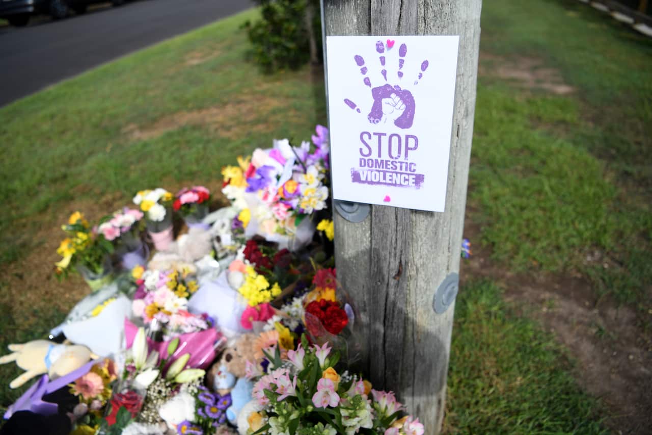 A sign "Stop Domestic Violence" near the scene of a car fire 