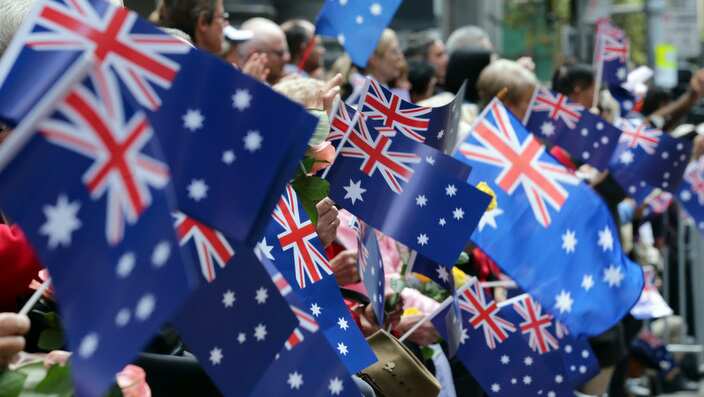 People wave flags as an ANZAC Day parade marches by in Sydney, Australia, Saturday, April 25, 2015.
