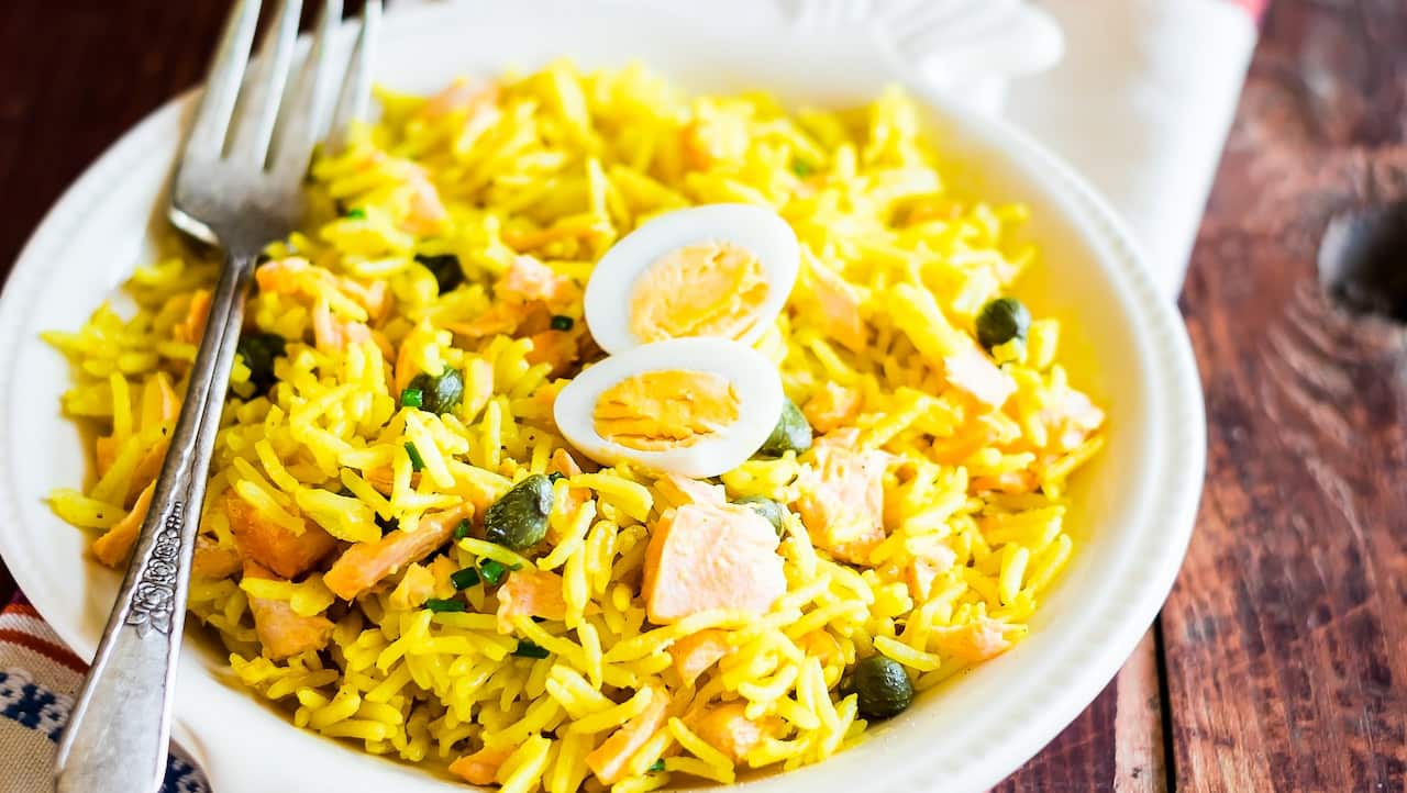 National scottish dish kedgeree with roasted basmati rice, curry powder, eggs and fish in a plate on a wooden table, selective focus. Image with copy space.
