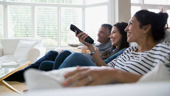 Family watching TV on living room sofa