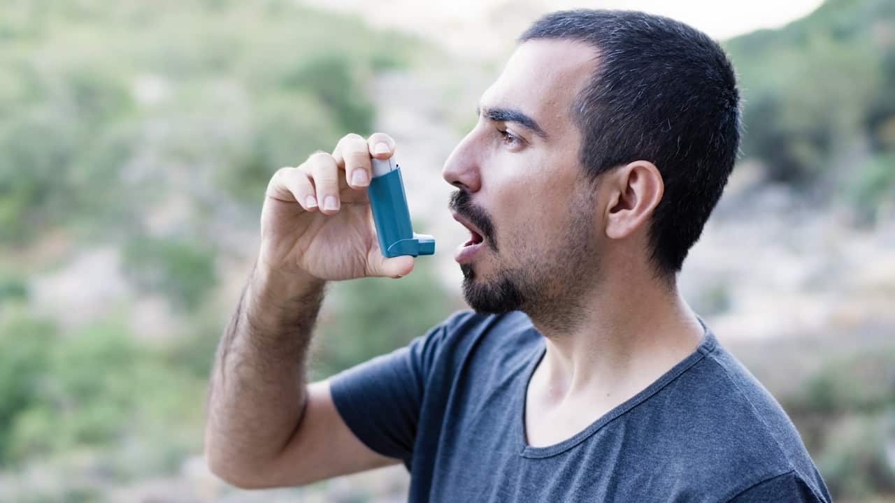 Young man using an asthma inhaler