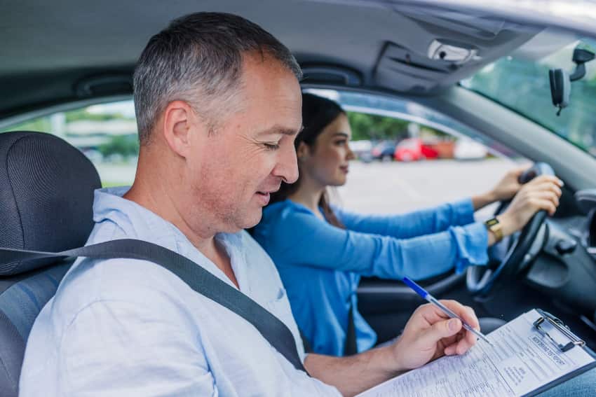 Young woman is driving with a supervisor