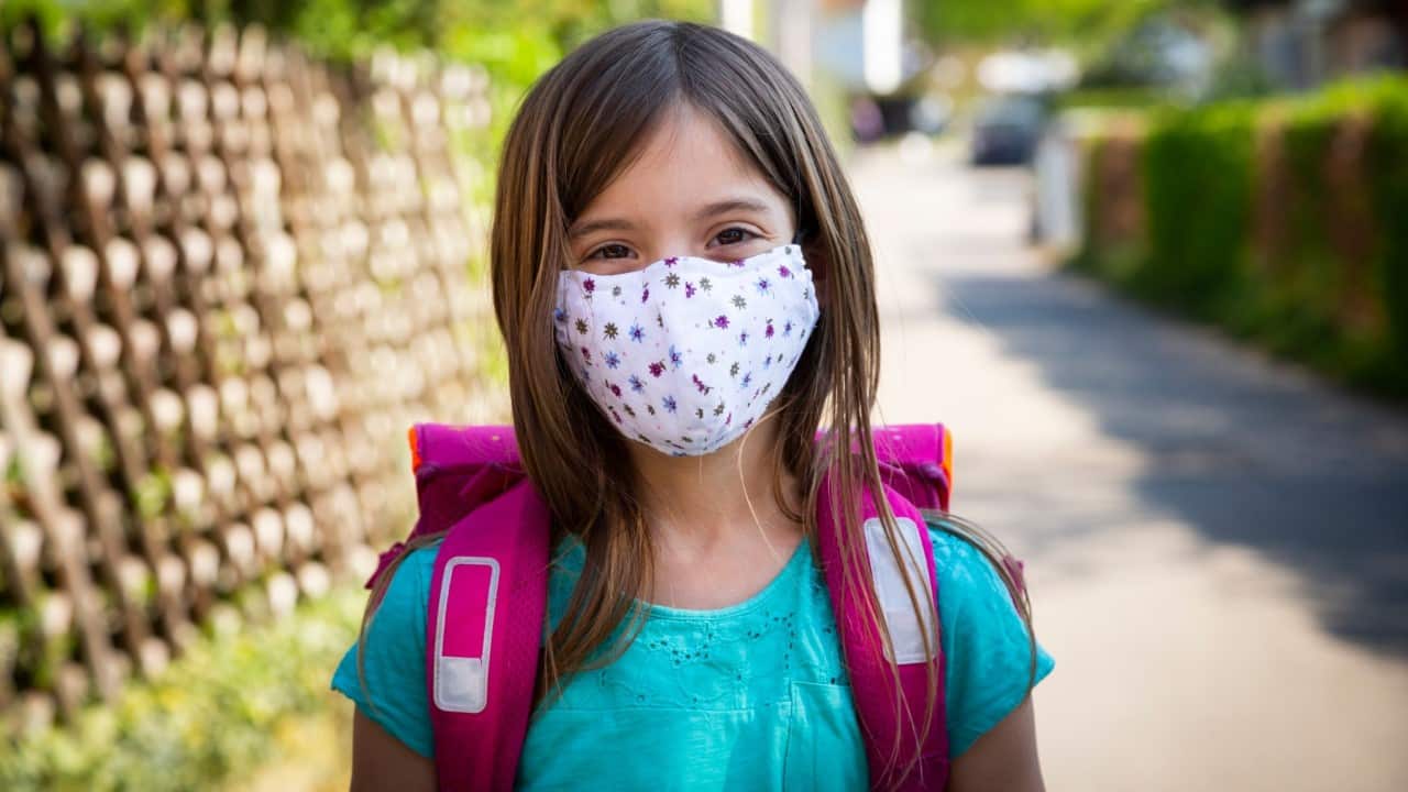 Girl wearing mask with a school bag