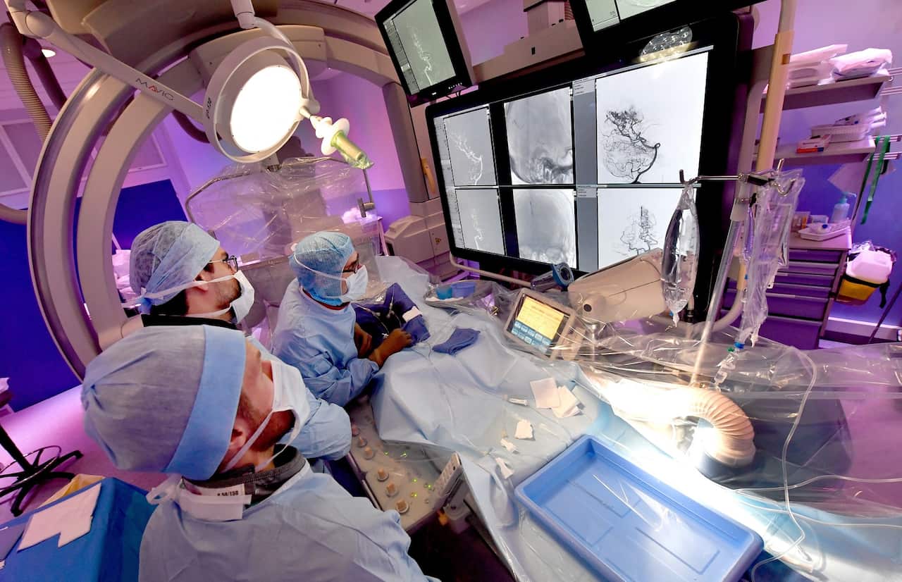 Neuro radiologists operate a patient