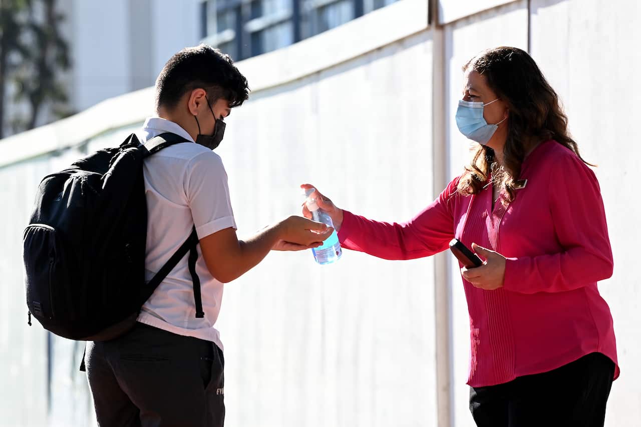 Hand sanitise and face masks are provided to students in a high school in Sydney.