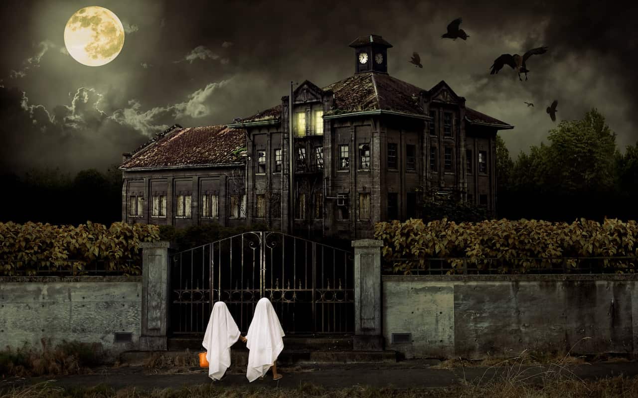 Children in Ghost Costumes Trick or Treat at Haunted House