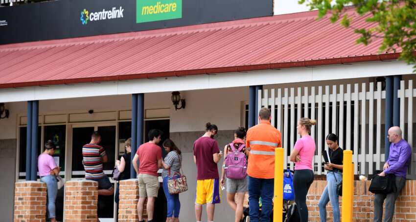 People are seen in a long queue outside a Centrelink.