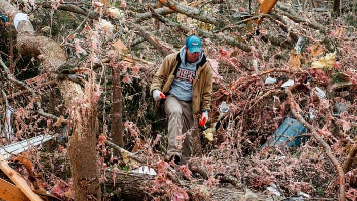 Joey Roush walks through the debris of his mother's home after it was destroyed in a tornado in Beauregard, Alabama 