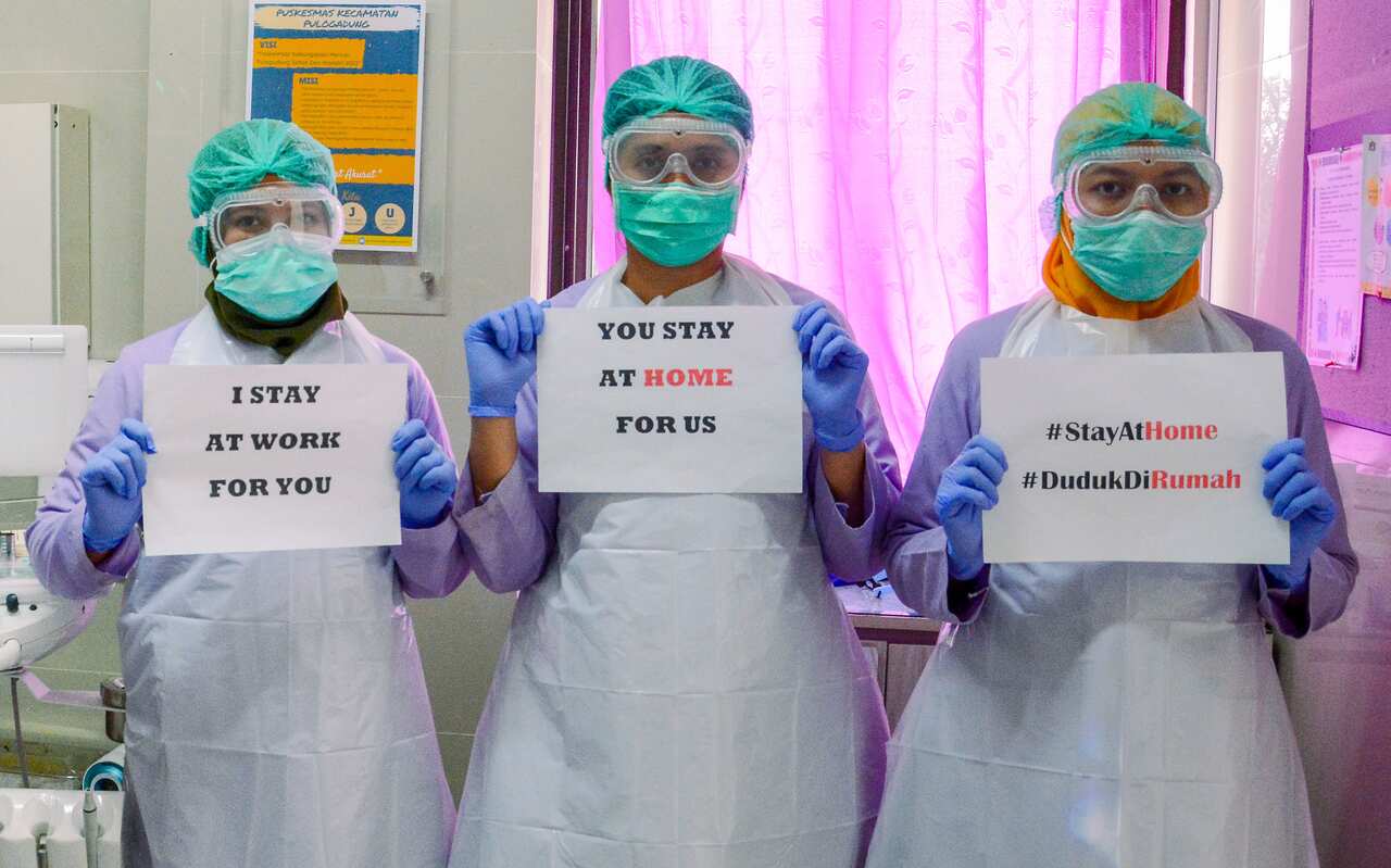 COVID-19. Medical workers wearing a face mask holds a 'Stay at Home' poster at a medical centre in Jakarta, Indonesia, on March 19, 2020.