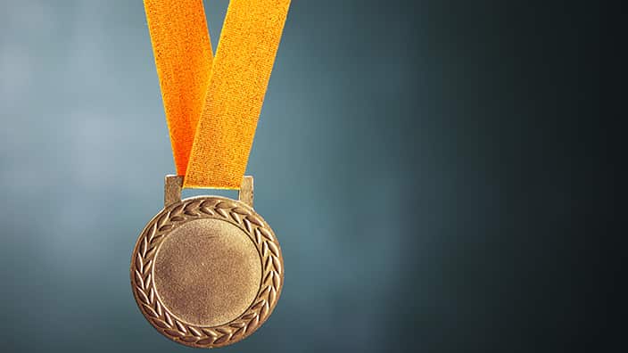 Close-Up Of Gold Medal Against Blackboard