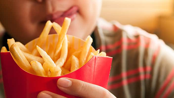 Cropped Image Of Tempted Boy Holding French Fries Packet