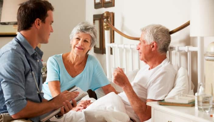 Doctor On Home Visit Discussing Health Of Senior Male Patient With Wife