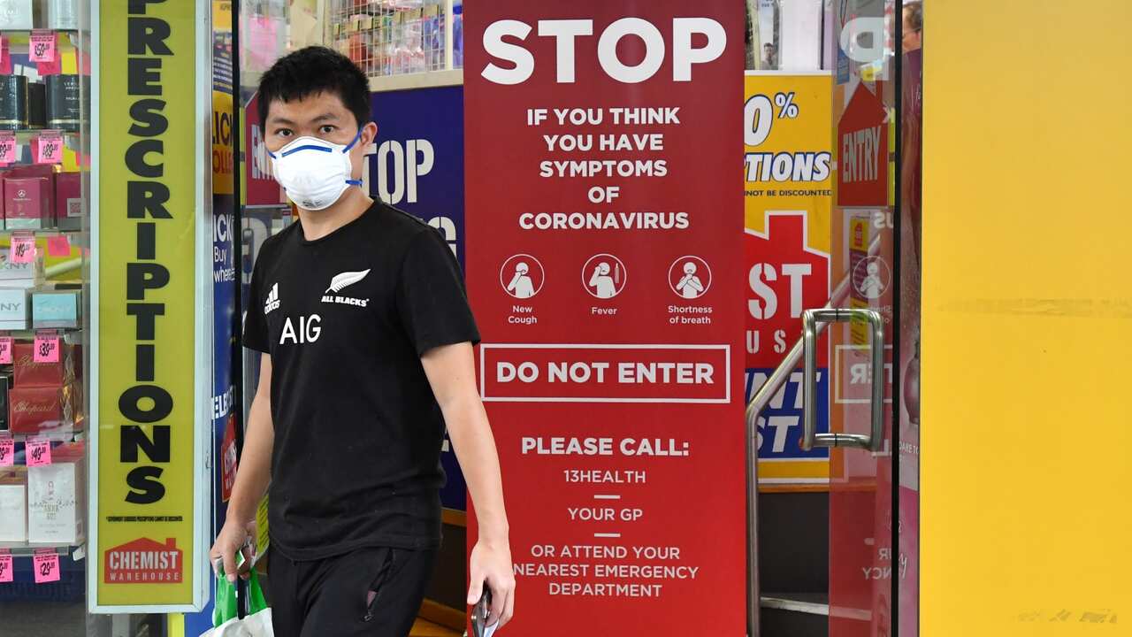 A customer wearing a protective face mask is seen leaving a pharmacy on Edward Street in Brisbane