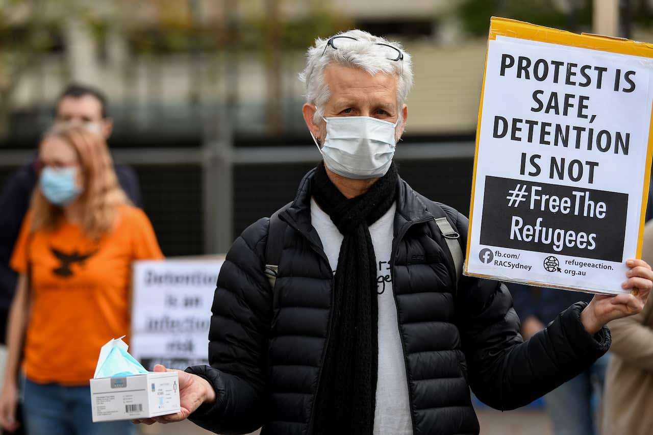 Protesters hold placards during a "Free The Refugees" rally at Sydney Town Hall in Sydney, Saturday, June 13, 2020. The Supreme Court on Thursday prohibited the protest from going ahead. (AAP Image/Bianca De Marchi) NO ARCHIVING