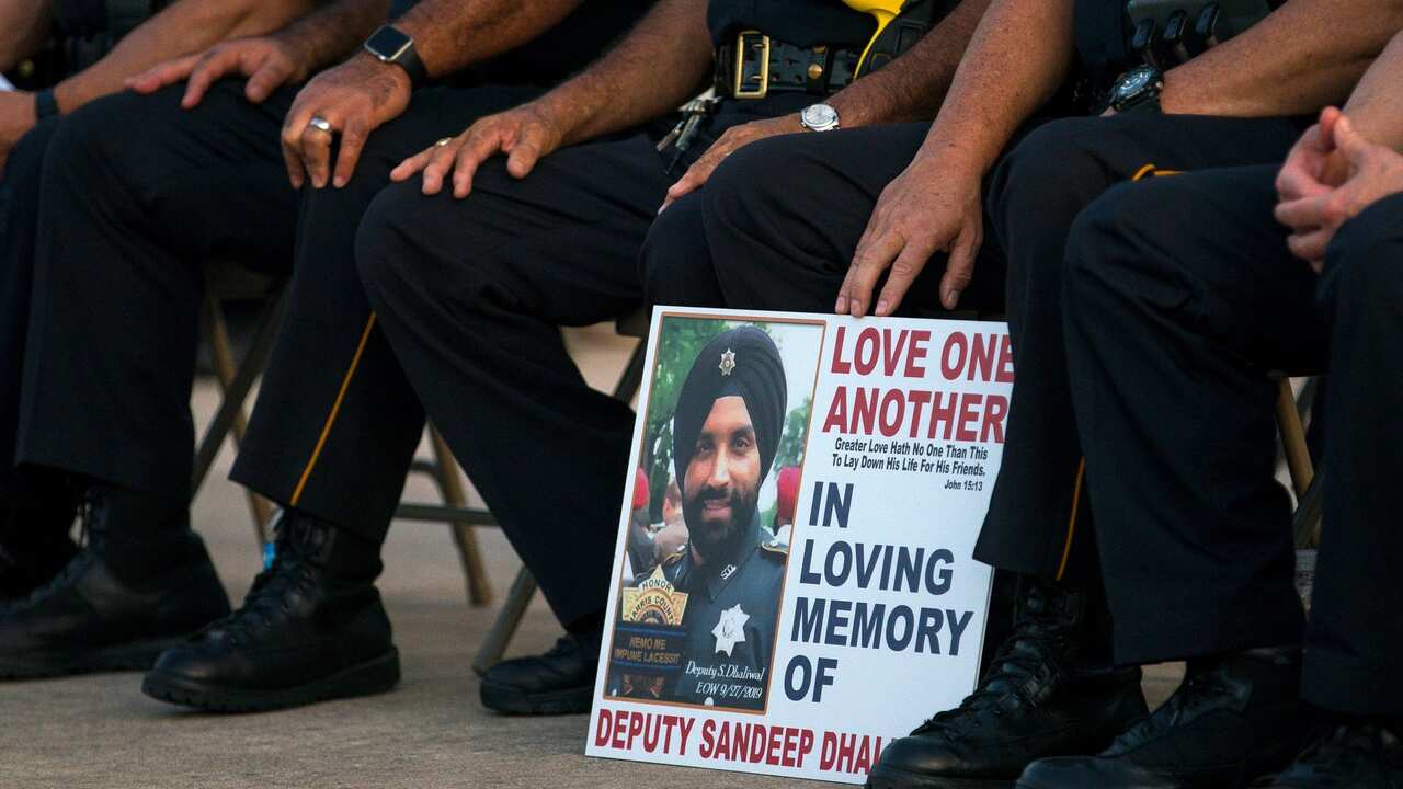 Harris County Sheriff's Office deputies hold a sign during a vigil for Harris County Sheriff's Office Deputy Sandeep Dhaliwal in Houston on September 30.