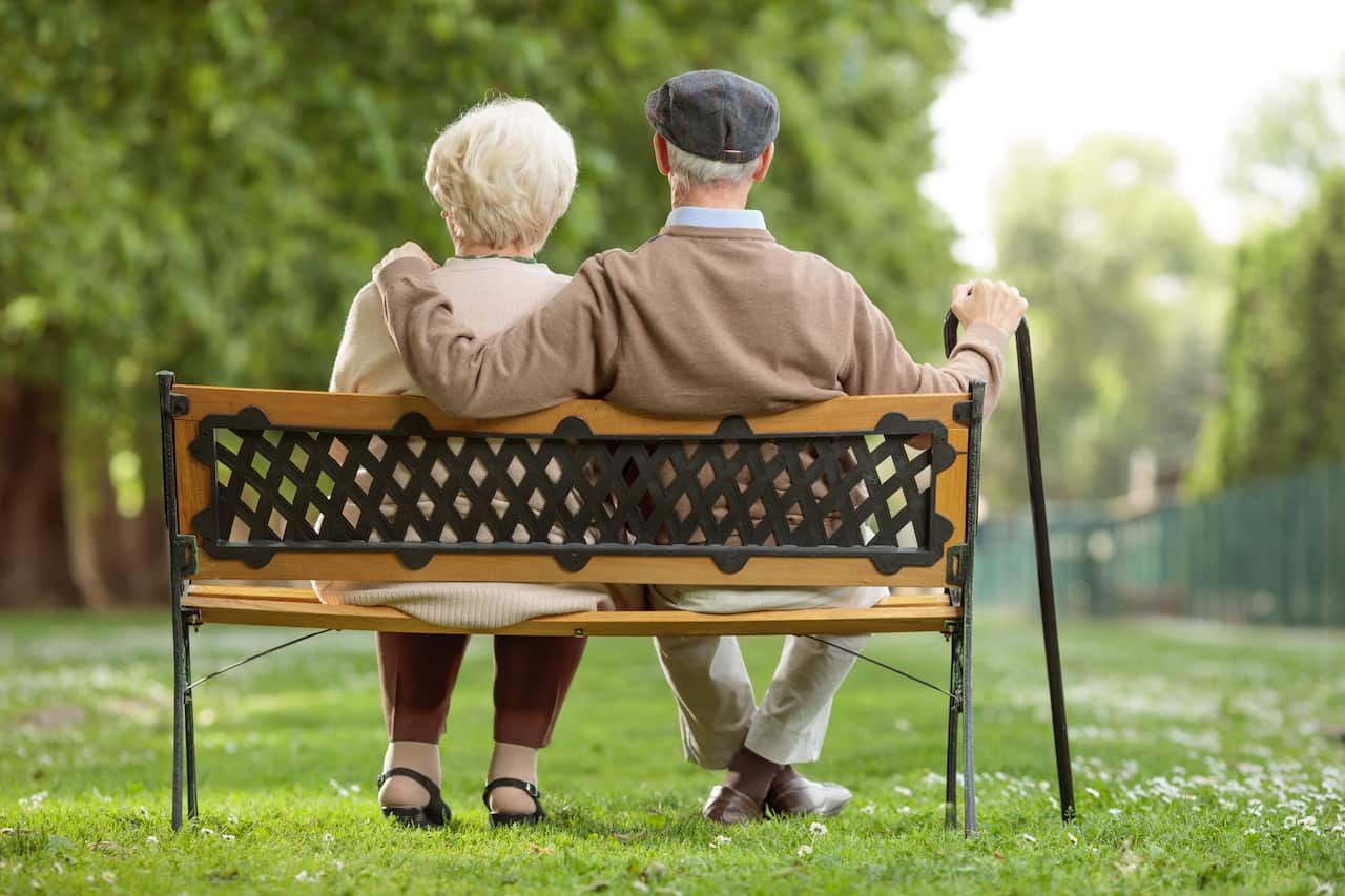 Senior couple sitting on a wooden bench in a park 