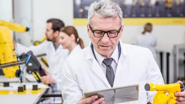 Engineer holding tablet and model of an industrial robot