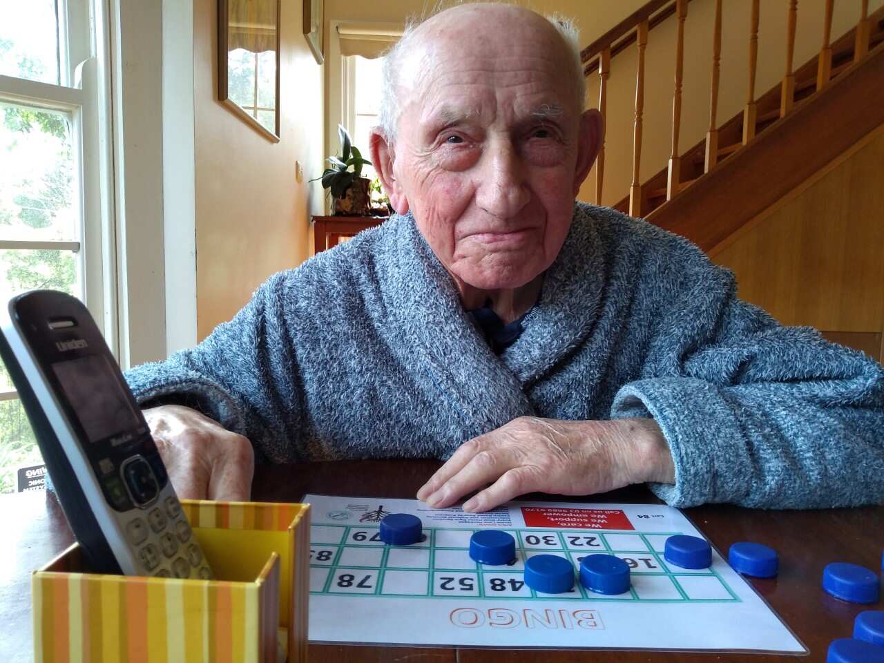 An elderly man playing bingo on the phone during isolation from the pandemic in Melbourne.