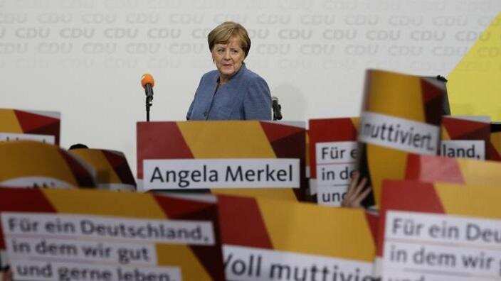 Supporters hold posters as German Chancellor Angela Merkel returns on the stage at the headquarters of the Christian Democratic Union CDU in Berlin.