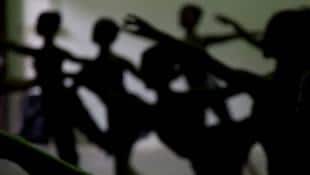 Dance students rehearse as lights flicker on and off in the ballet studio running from reserve generators