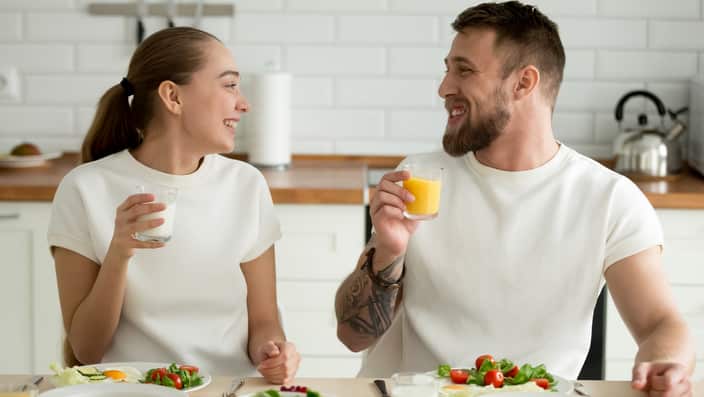 Smiling couple drinking orange juice and buttermilk while enjoyi