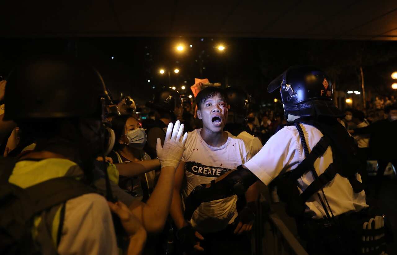 A man (C) is detained by police after getting into a fight with anti-extradition protesters outside the Kwai Chung police station in Hong Kong, China, 30 July