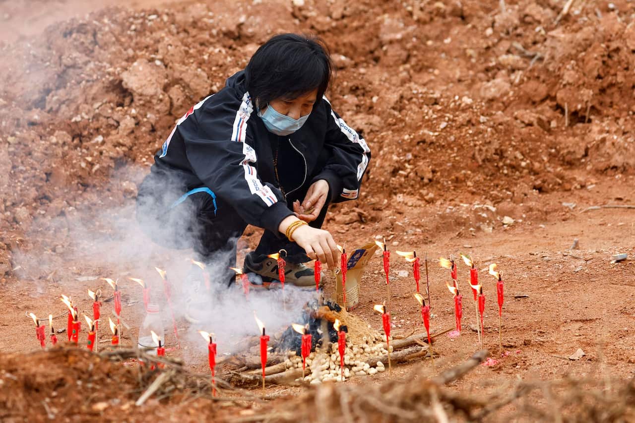 A woman surnamed Liang, 60, takes part in a Buddhist ceremony in honor of the victims in a field near the crash site.