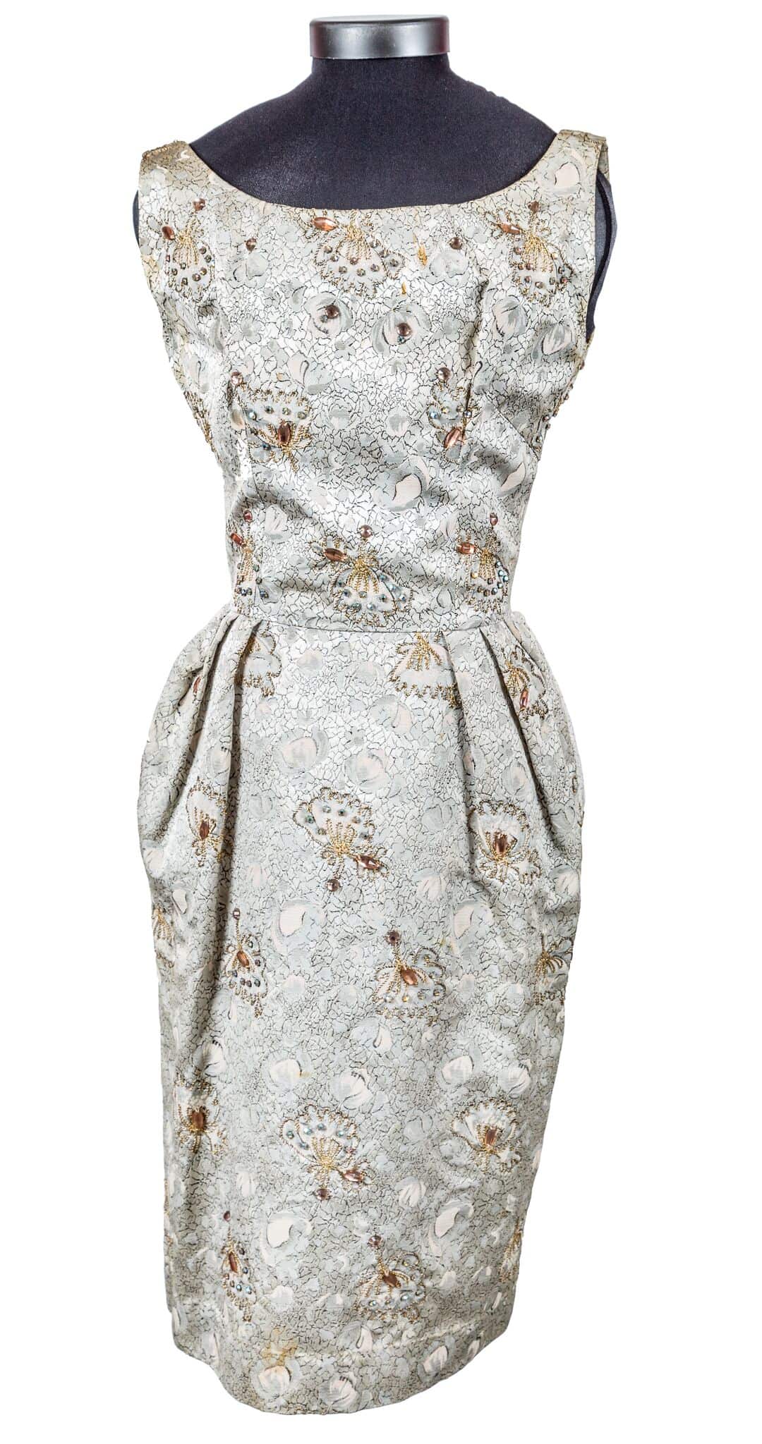 White coloured silk, jacquard with gold, silver and apricot flowers.  Flowers are augmented by small glass beads.