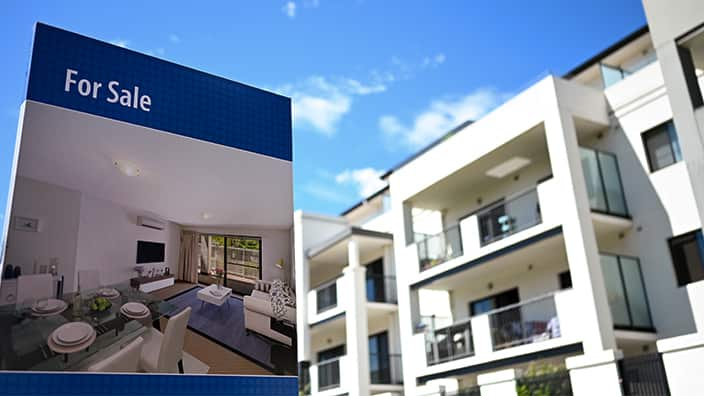 A real estate advertising board is seen next to a house