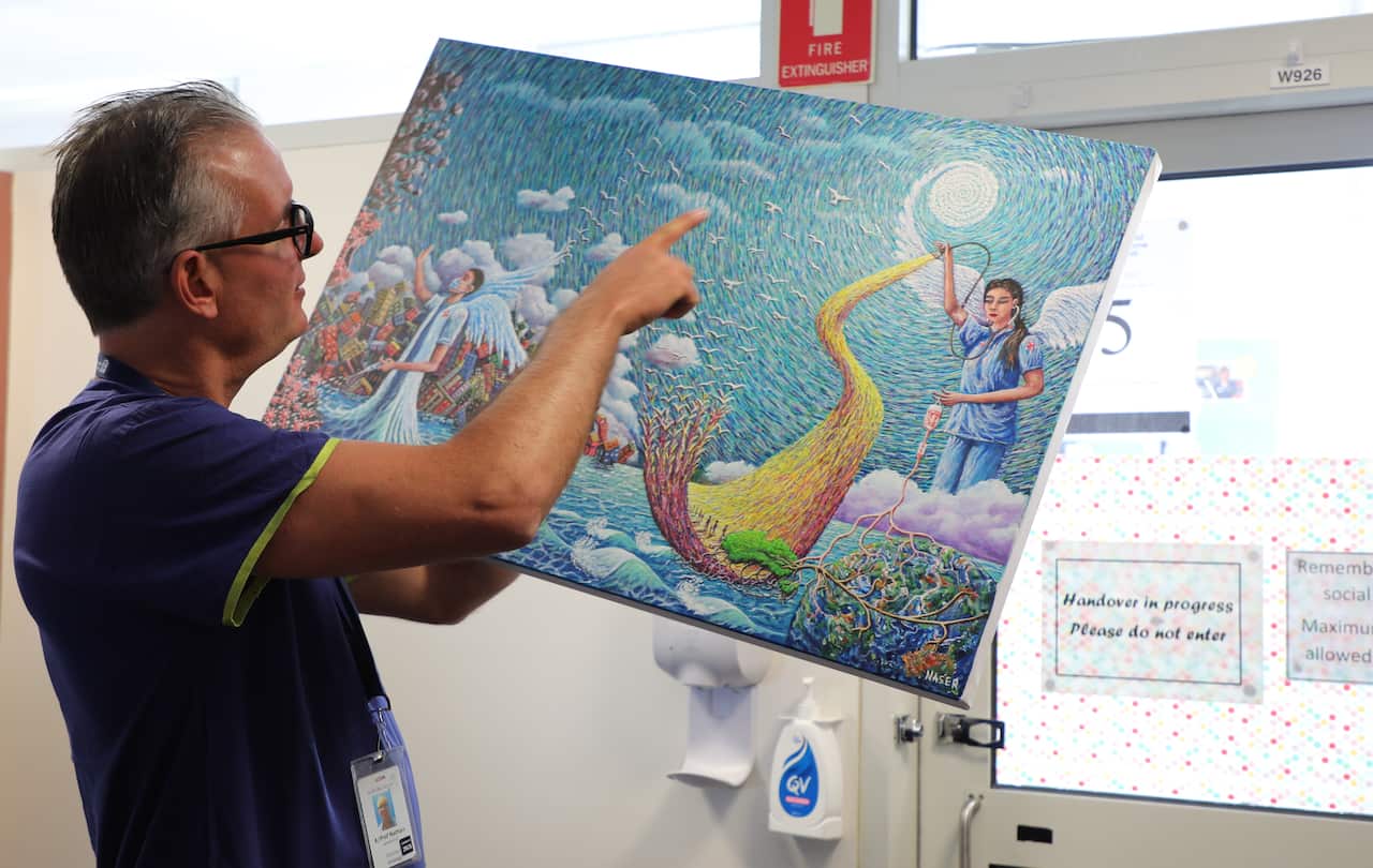 RMH head of urology Professor Nathan Lawrentschuk  pointing at Naser Moradi's painting. 