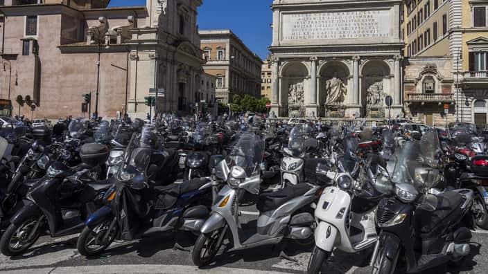 Rome is ranked among the cities with the most registered scooters in the world. Various scooters are parked in front of a historic building in Rome