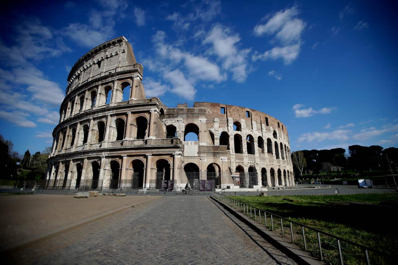 A man pedals in front of an empty area outside Rome's ancient Colosseum due to measures avoiding public gatherings to prevent the spread of Covid-19, Thursday, April 2, 2020. Rome's ancient Colosseum, Thursday, April 2, 2020. The new coronavirus causes mi