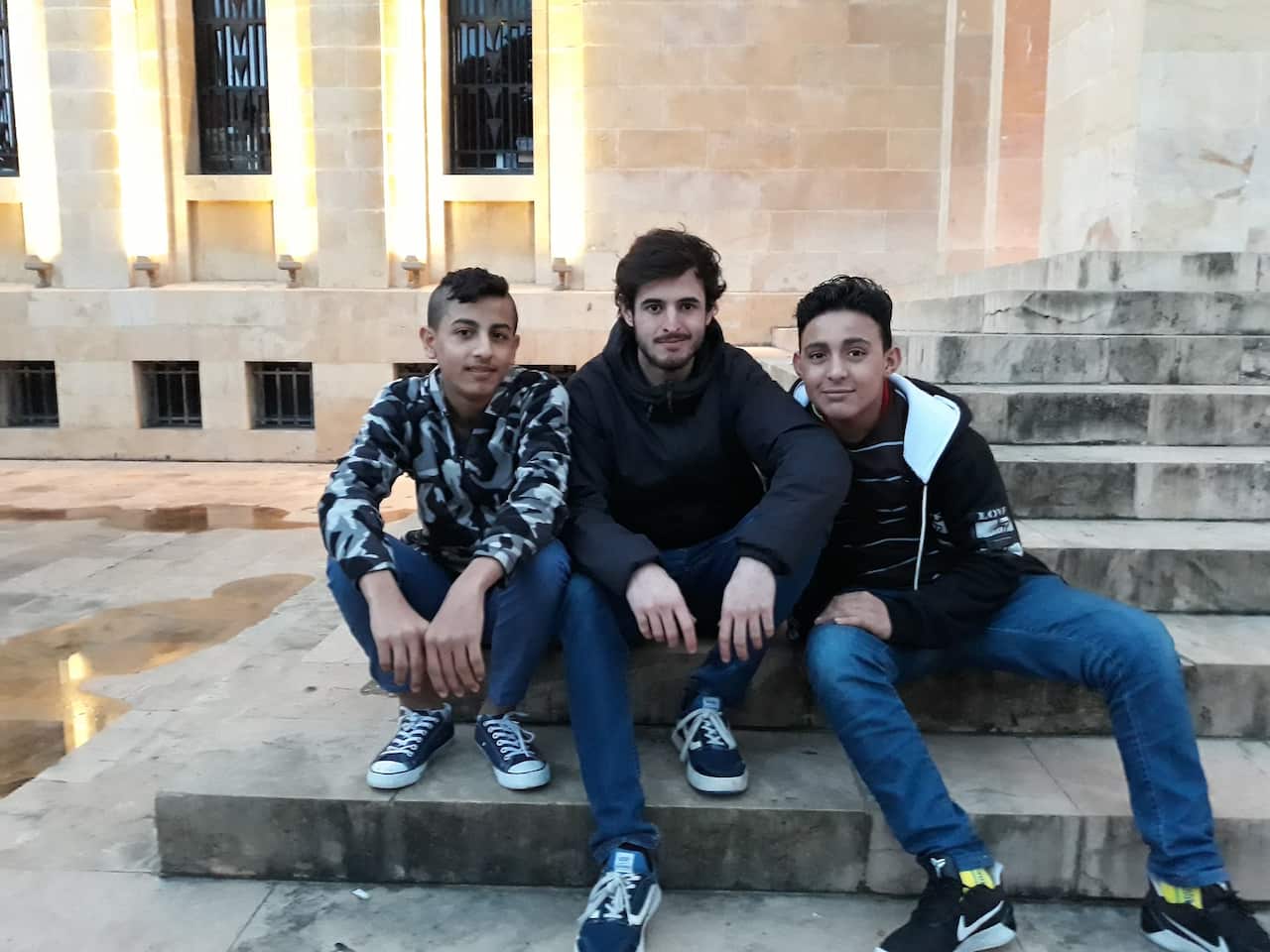 German, 26 Letters co-founder, sitting with students Salah and Janira.