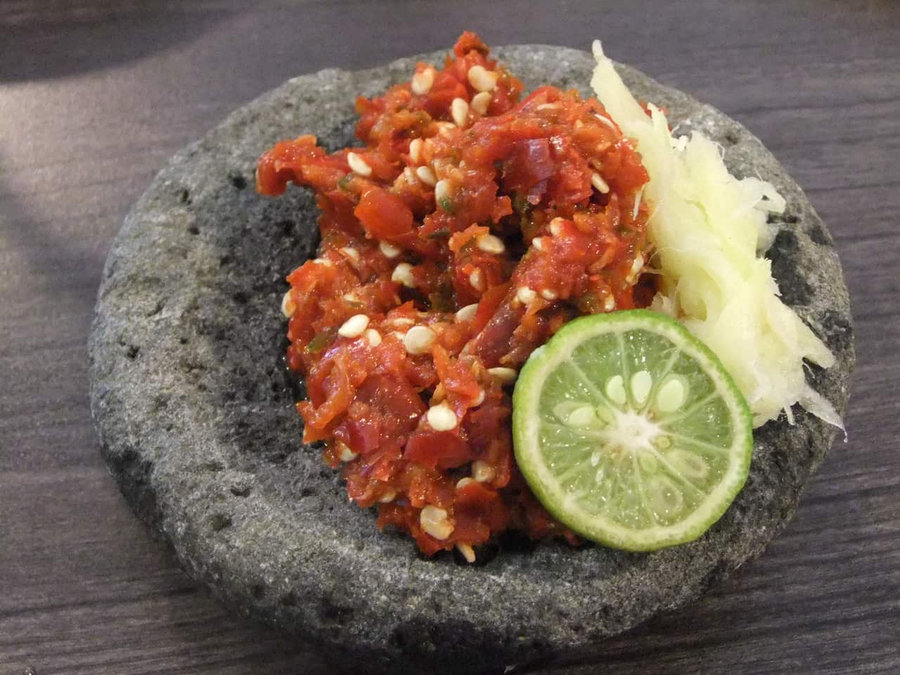 Traditional sambal terasi served on stone mortar with garlic and lime.