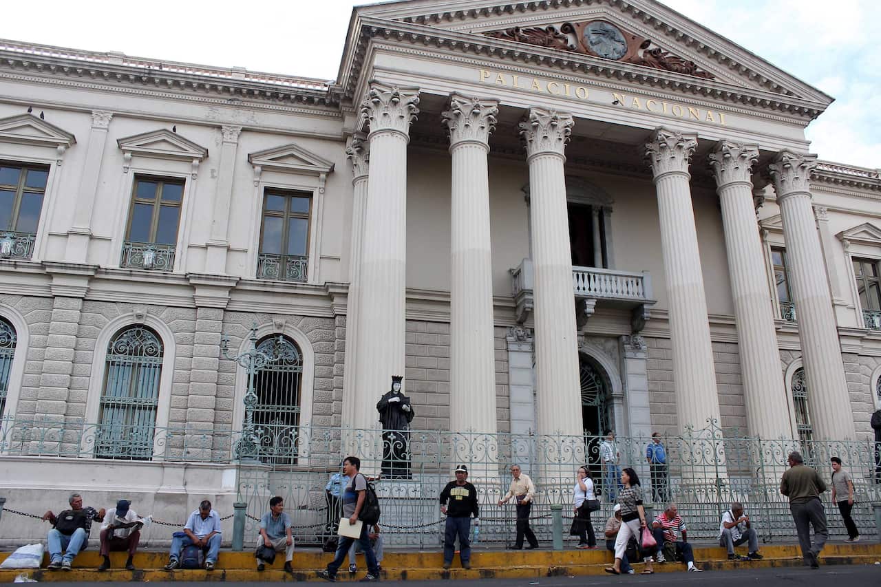 people walk in front of the National Palace in San Salvado