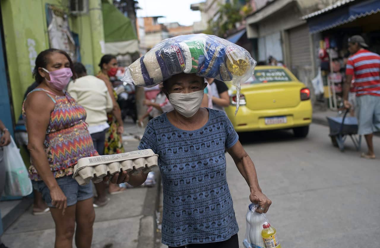 Woman delivering food to people struggling due to the new coronavirus pandemic, at the Para-Pedro favela in Rio de Janeiro, Brazil.